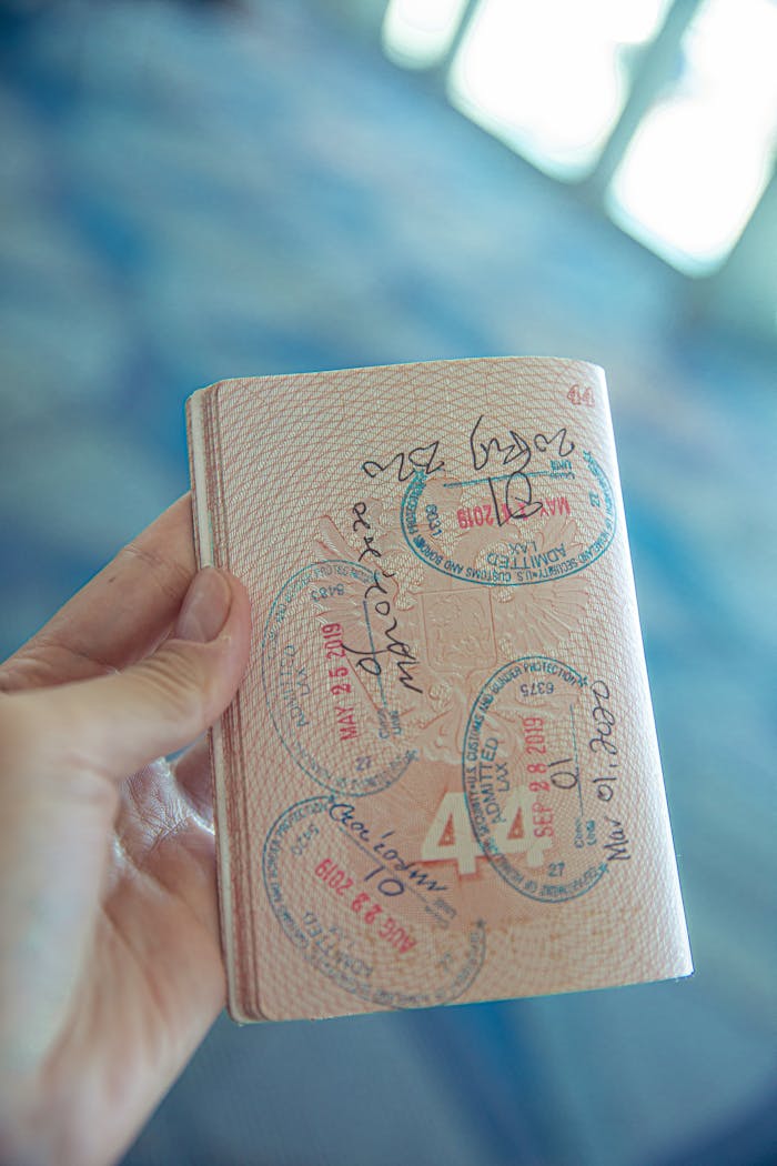 why-choose-us-02 A close-up view of a hand holding an open passport with various stamps, highlighting travel experiences.